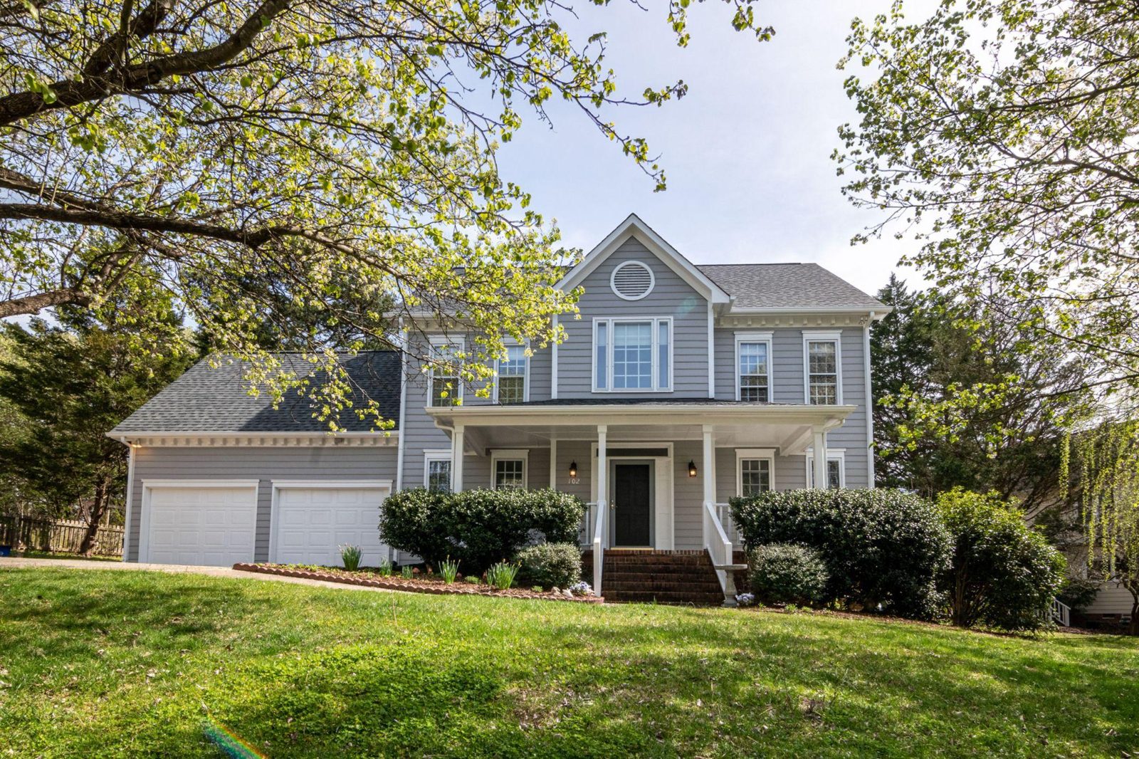 A two-story suburban house with a gray exterior, two-car garage, and green lawn